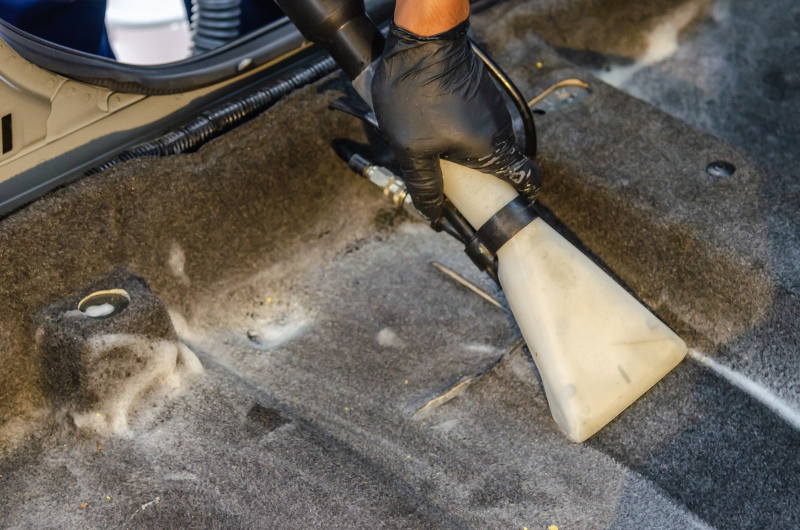 Carpet extractor pulling dirt from a car floor mat