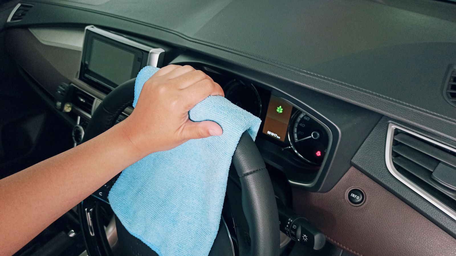 Detailer wiping down a car dashboard with a microfiber towel